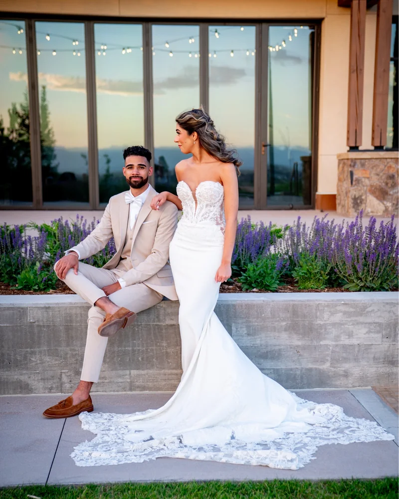 Groom lifting his bride on the lawn as her cathedral veil sweeps behind, castle venue behind them
