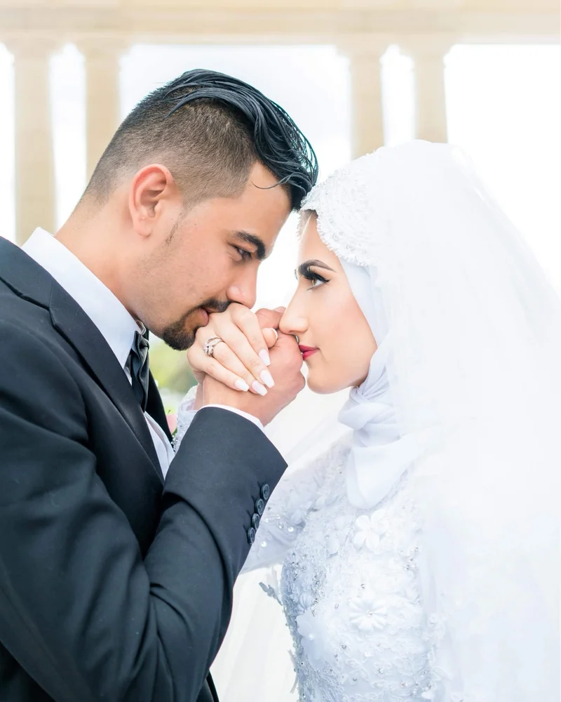 Groom bowing to kiss his bride's forehead, her hands cupping his face