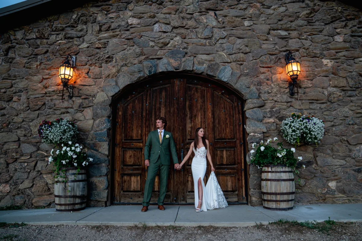 Bride and groom seated together against a wall of warm venue windows at dusk